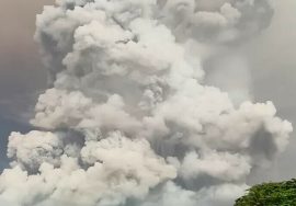 A massive cloud of volcanic ash rising high into the sky, forming thick white and gray plumes after a powerful eruption.