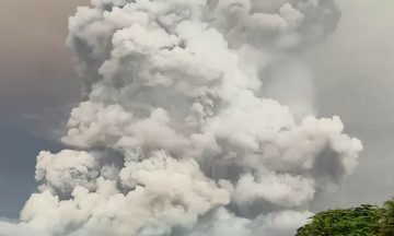 A massive cloud of volcanic ash rising high into the sky, forming thick white and gray plumes after a powerful eruption.