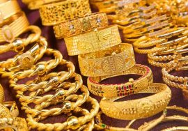 A close-up view of various gold bangles and bracelets arranged on a display counter in a jewelry shop.
