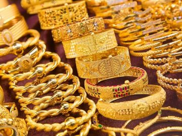 A close-up view of various gold bangles and bracelets arranged on a display counter in a jewelry shop.