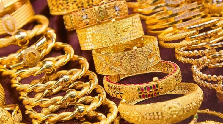 A close-up view of various gold bangles and bracelets arranged on a display counter in a jewelry shop.