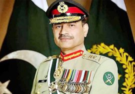 Portrait of Field Marshal Asim Munir in military uniform standing in front of Pakistan flags.