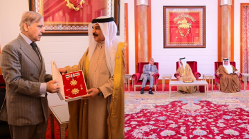 Two combined images showing a formal ceremony in Bahrain. In the first image, Pakistan’s Prime Minister Shehbaz Sharif receives an official state honor from Bahrain’s King, who is presenting a red and gold medal set inside an open display box. Both leaders are standing and engaged in conversation. In the second image, Shehbaz Sharif is seated with Bahraini leadership in an ornate hall decorated with red carpets, golden pillars, and a large framed Bahrain emblem on the wall.