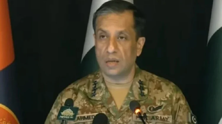A Pakistani military spokesperson, Lieutenant General Ahmed Sharif, delivering an official press briefing at a podium with microphones. The backdrop shows Pakistan Army flags and branding. The screen displays a breaking news headline summarizing his statement about Pakistan targeting only terrorists and never civilians.