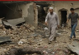 Two men walking through the debris of a destroyed building after an explosion in Pakistan.