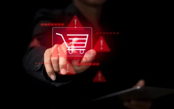 A person touching a glowing red shopping cart icon with warning symbols, representing online shopping scams and cybersecurity risks.