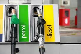 Fuel station pumps showing two nozzles side-by-side — one labeled petrol in green and the other labeled diesel in yellow.
