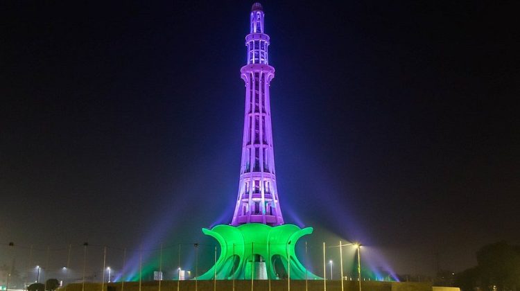 Minar-e-Pakistan illuminated at night with vibrant green and purple lights, showcasing the landmark’s architectural beauty.