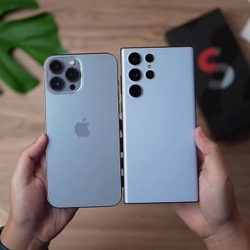 "Two modern smartphones held side by side, showcasing their rear camera designs in a comparison view."