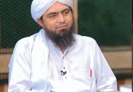 "A religious scholar wearing traditional white attire and a turban seated during a discussion program."
