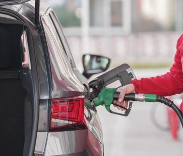 A person refueling a car at a petrol pump using a green fuel nozzle, representing rising petrol and diesel prices and fuel cost increase in Pakistan.