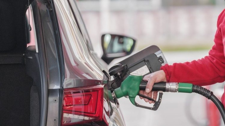 A person refueling a car at a petrol pump using a green fuel nozzle, representing rising petrol and diesel prices and fuel cost increase in Pakistan.