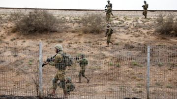 "Israeli soldiers patrolling near border fence in desert terrain during Gaza conflict tensions."