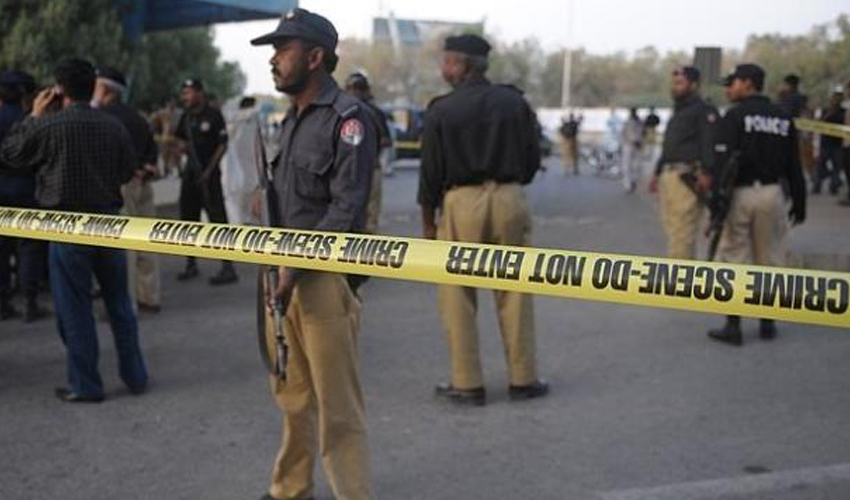 Police officers standing behind yellow crime-scene tape at a sealed-off area during an investigation.